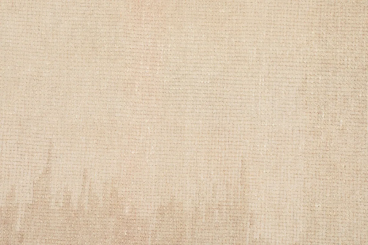 Close-up texture of the low wool pile of the beige rug, showing its soft finish and subtle variations.