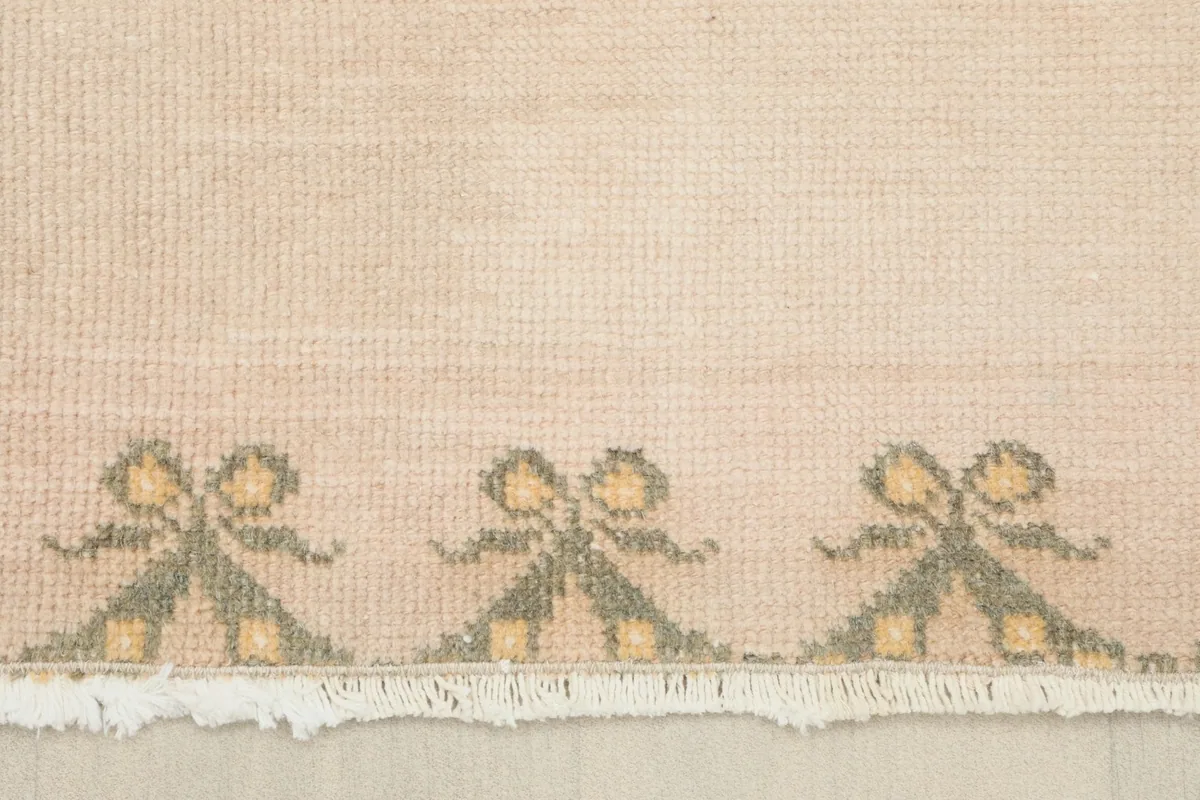 Detail of the fringe and a section of the olive and gold border pattern at the end of the rug.