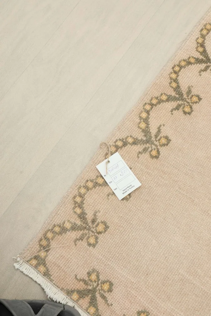 Close-up of the rug's border with a product tag, showing details of the hand-knotted craftsmanship.