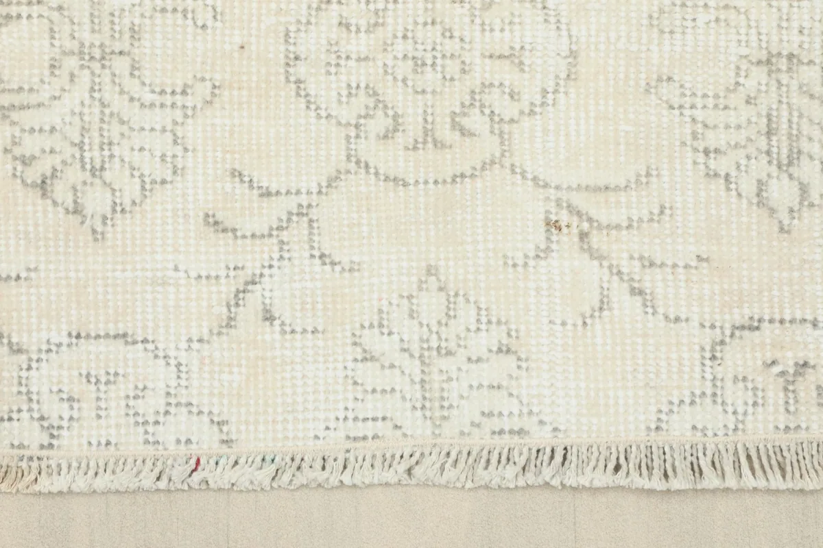 Close-up of the rug's fringe and a section of the ivory field with gray motifs