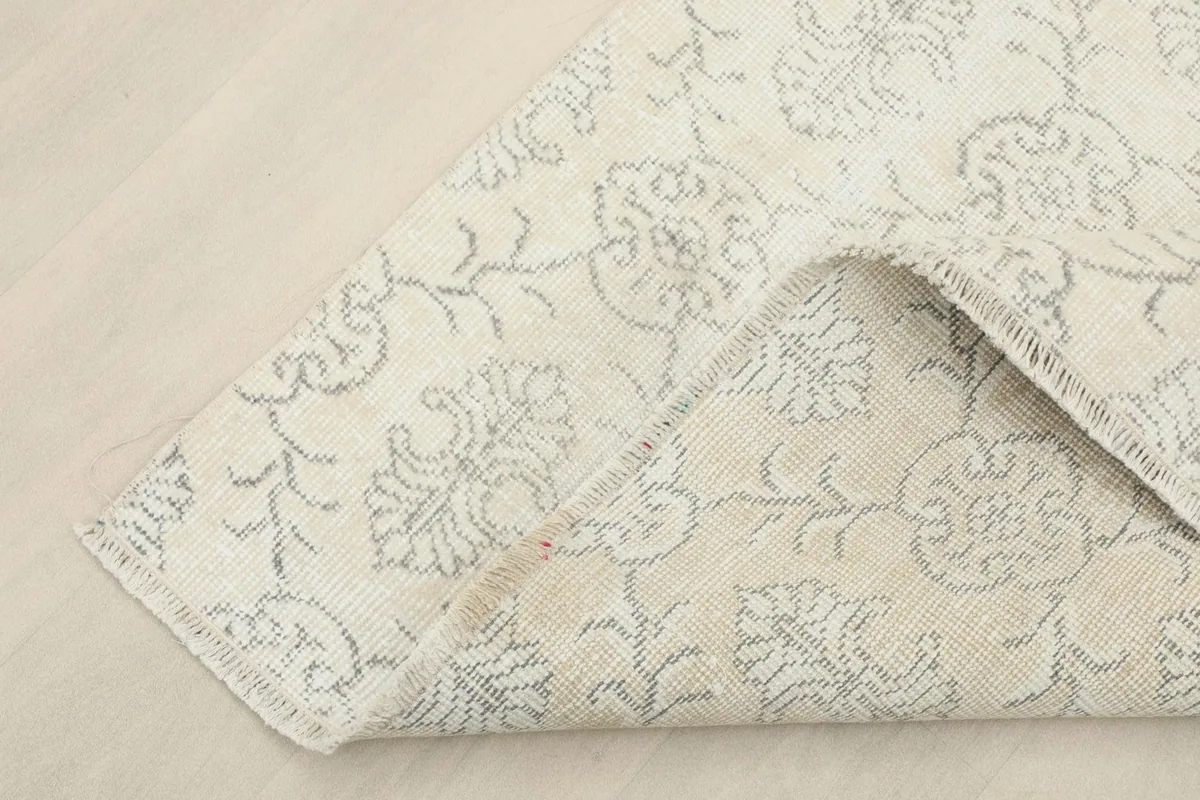 Corner of the rug folded to show the hand-knotted construction and back of the rug