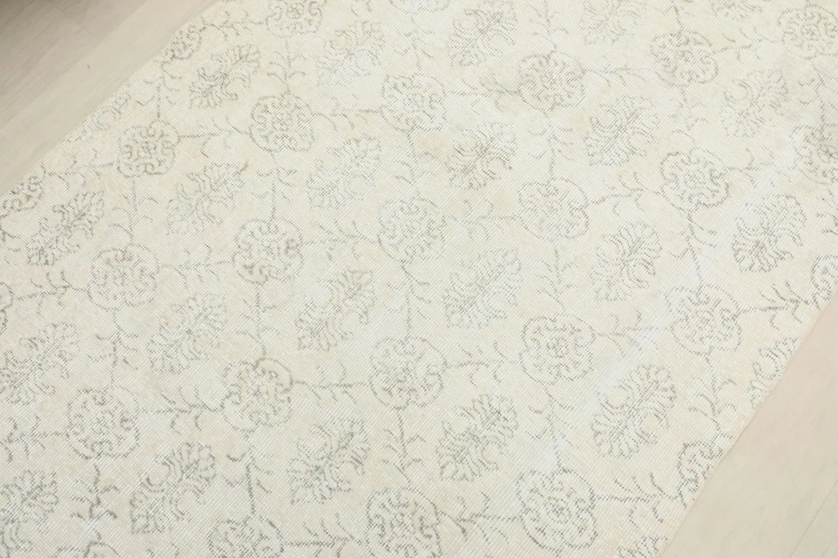 Overhead detail of the ivory field and gray floral and geometric motifs on the rug