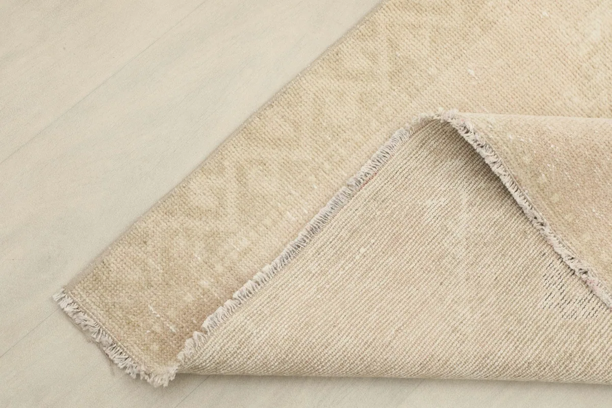 Corner of the rug folded back to show the cotton foundation and hand-knotted construction