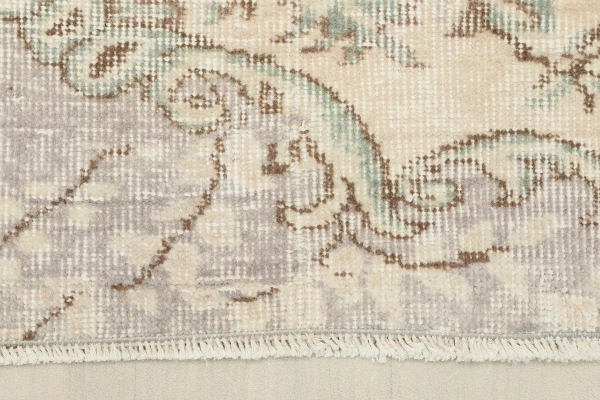 Close-up of the rug's border and fringe, showcasing the gray tones and the transition to the cotton foundation.