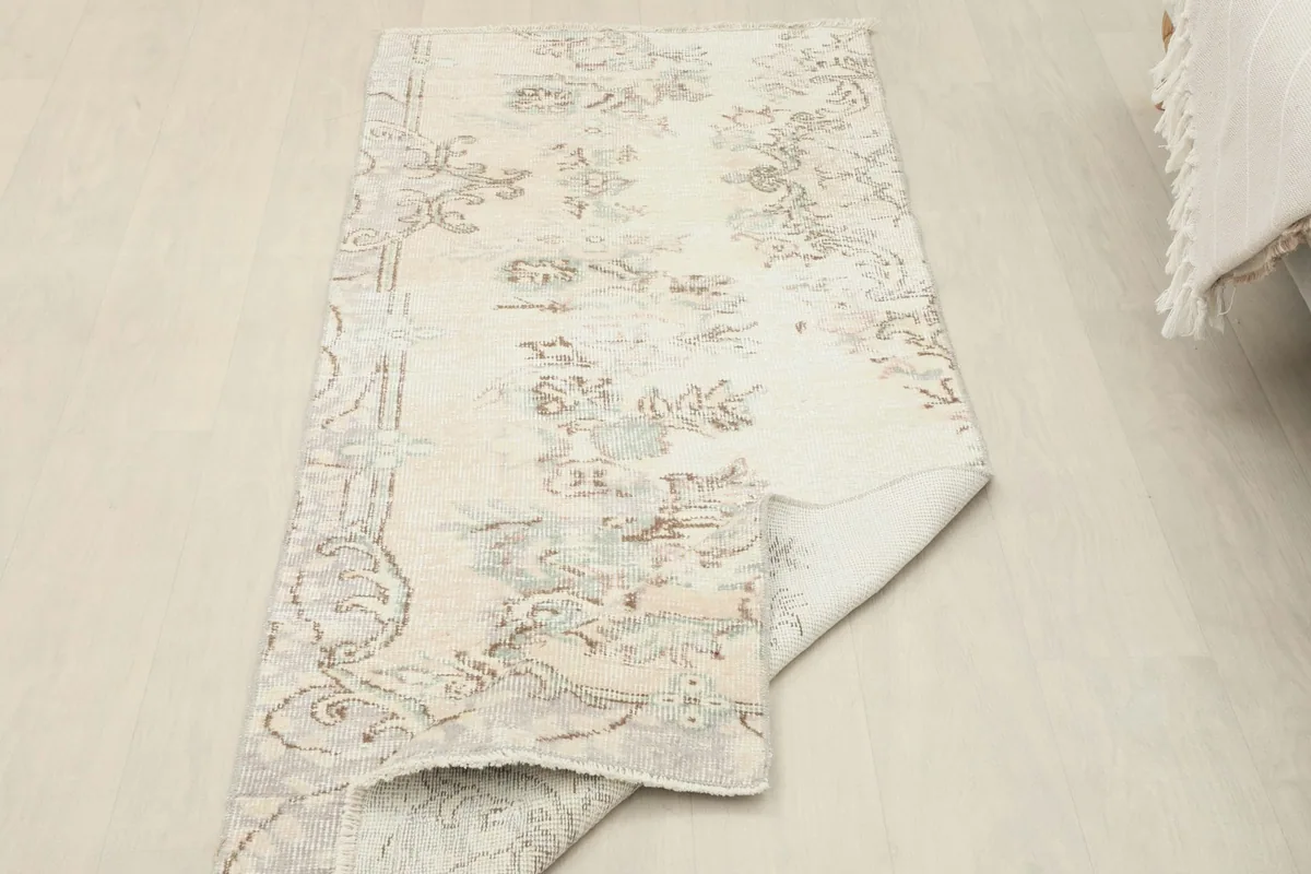 The ivory runner partially folded, illustrating its flexibility and the thickness of the low wool pile.