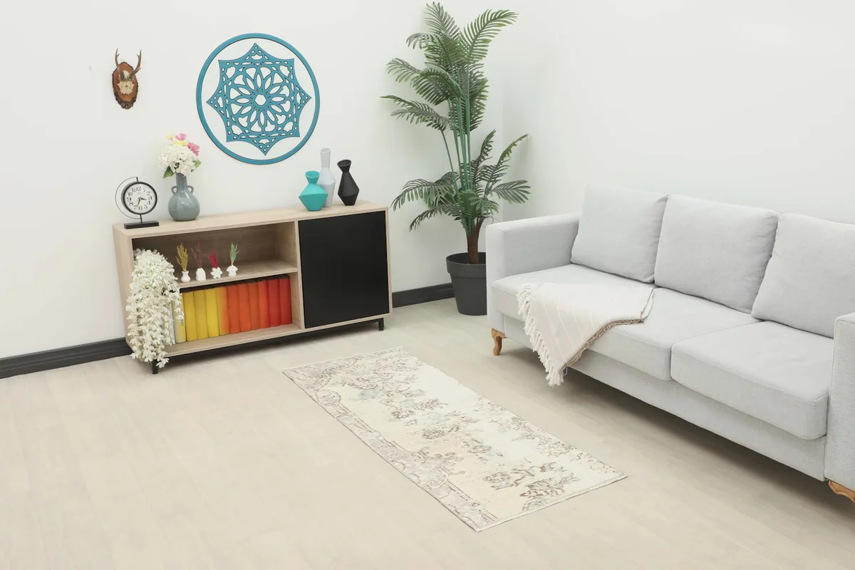 Ivory vintage runner rug displayed in a living room setting with a sofa and cabinet.