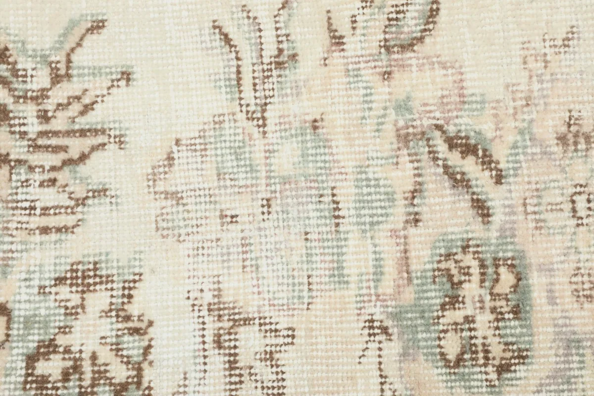 Close-up of the rug's wool pile, showing the hand-knotted detail and muted green and brown tones.