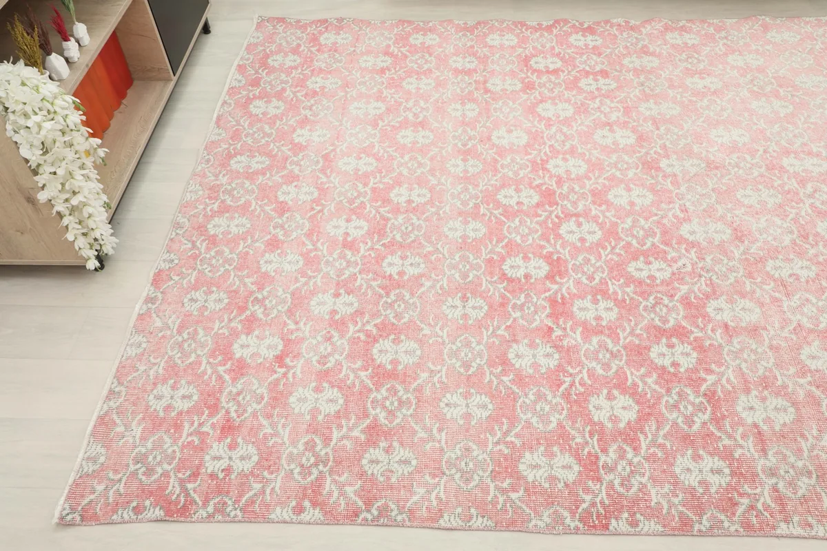 Wide shot of the pink vintage rug in a room, capturing its full pattern and colors from an elevated perspective.