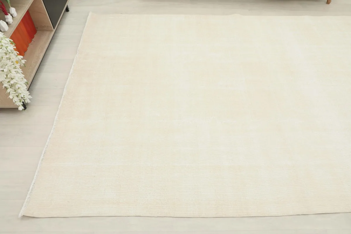 Corner view of the cream minimalist rug, showing its placement next to home decor.