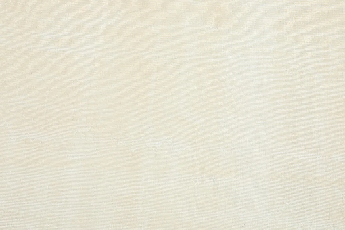 Close-up detail of the cream wool pile, revealing the subtle variations in tone and texture.
