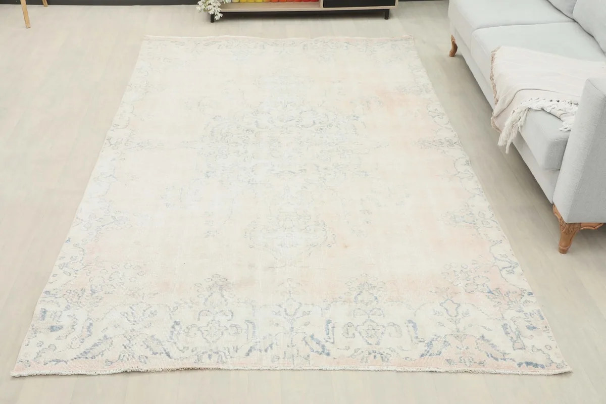 Full view of the 6x10 cream and blue vintage rug in a living room with a sofa and decor