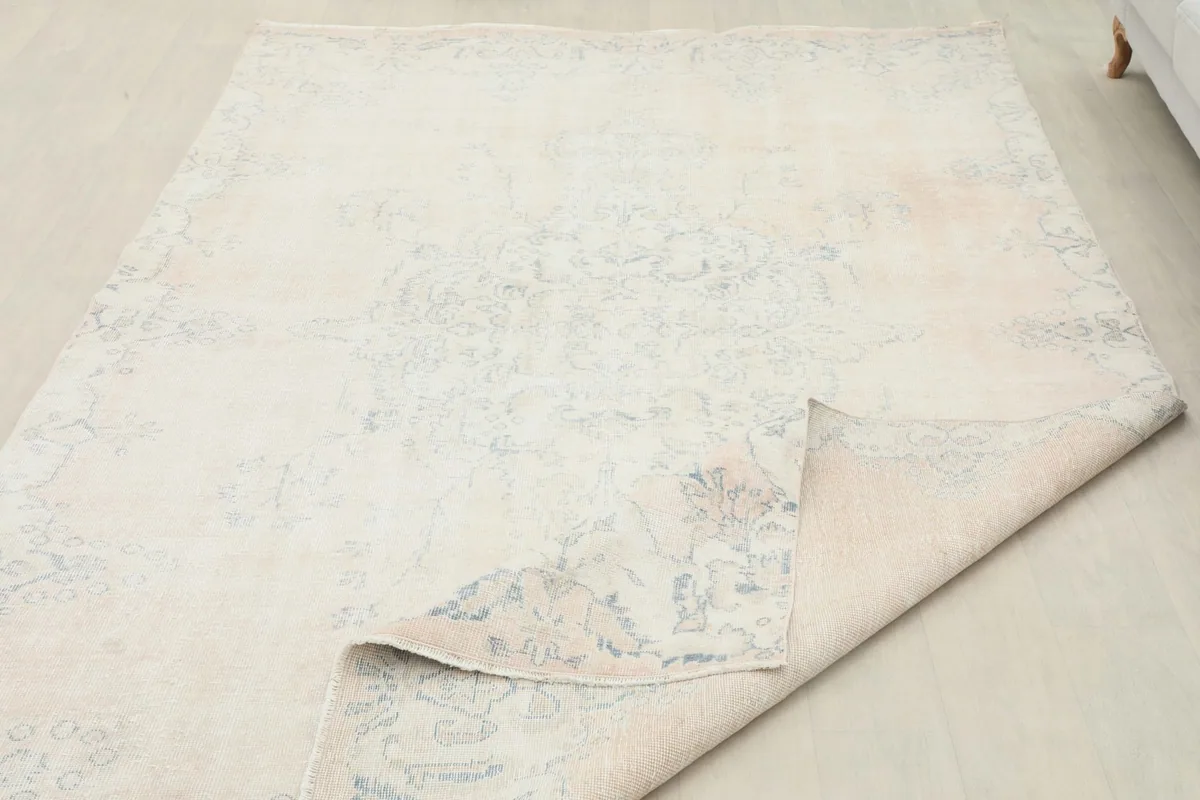View of the rug with a corner lifted, showing the back of the hand-knotted construction