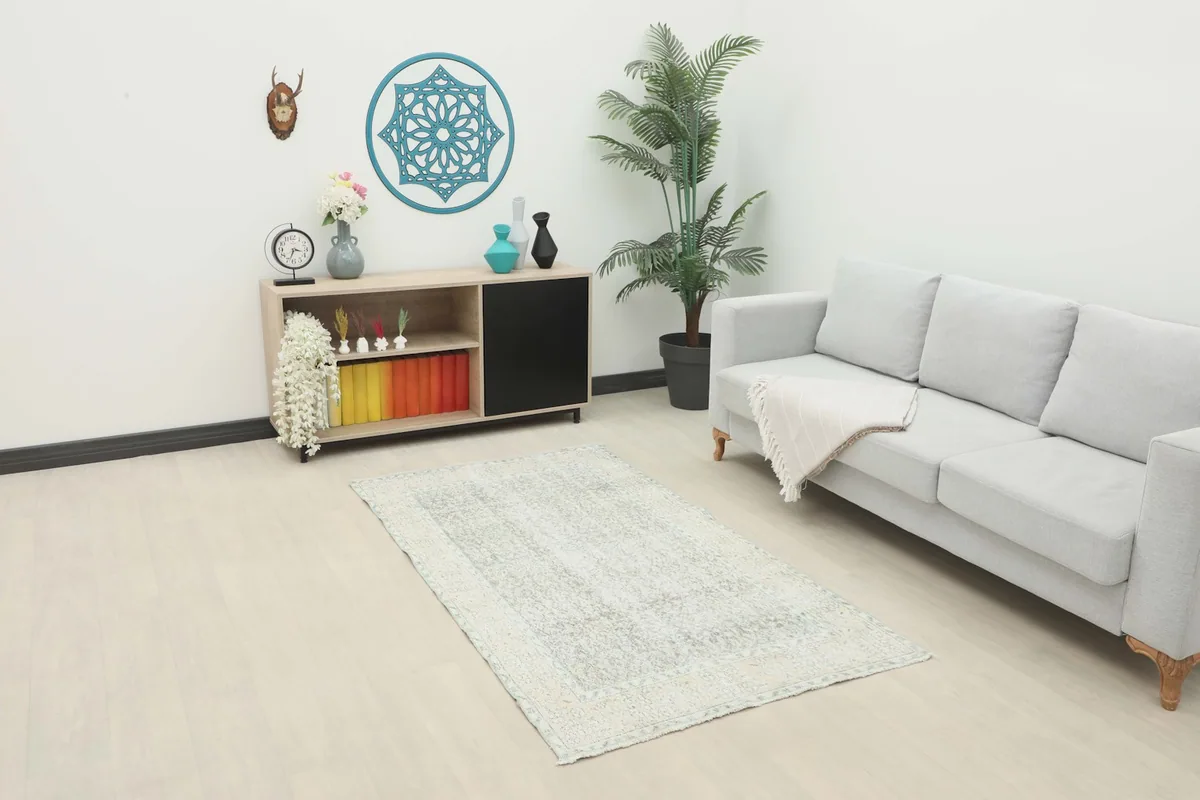 The small gray and cream rug placed in a living room setting with a light gray sofa and wooden cabinet.