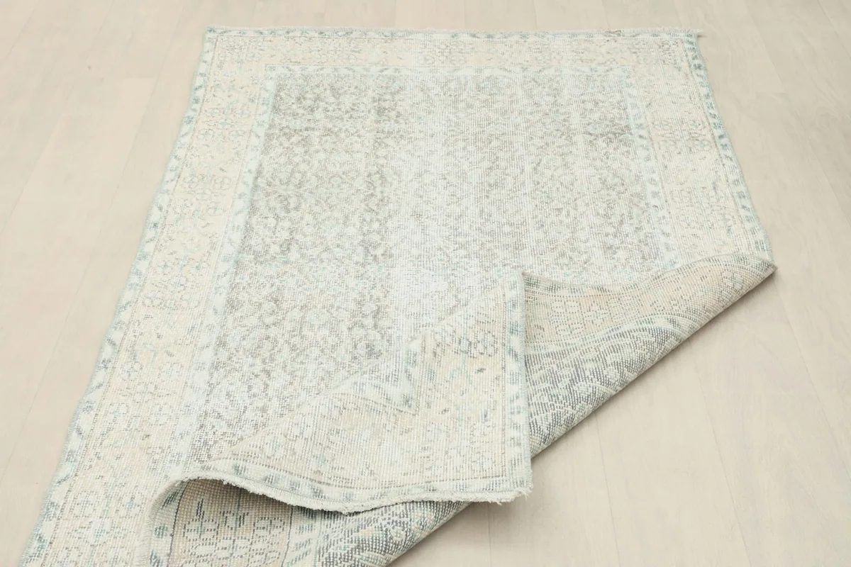 The rug partially folded, showing the flexibility and the reverse side with its cotton foundation.