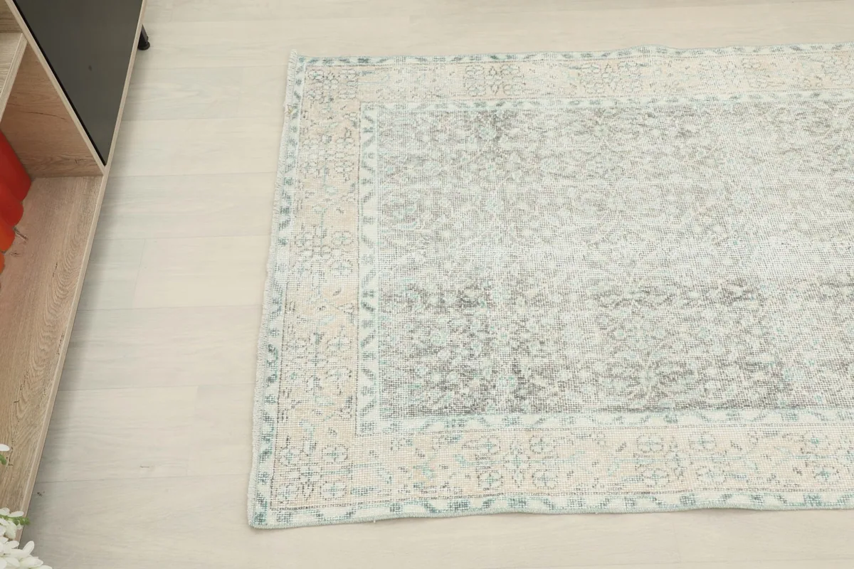 Overhead view focusing on a section of the rug, showing the blend of gray, cream, and blue tones.