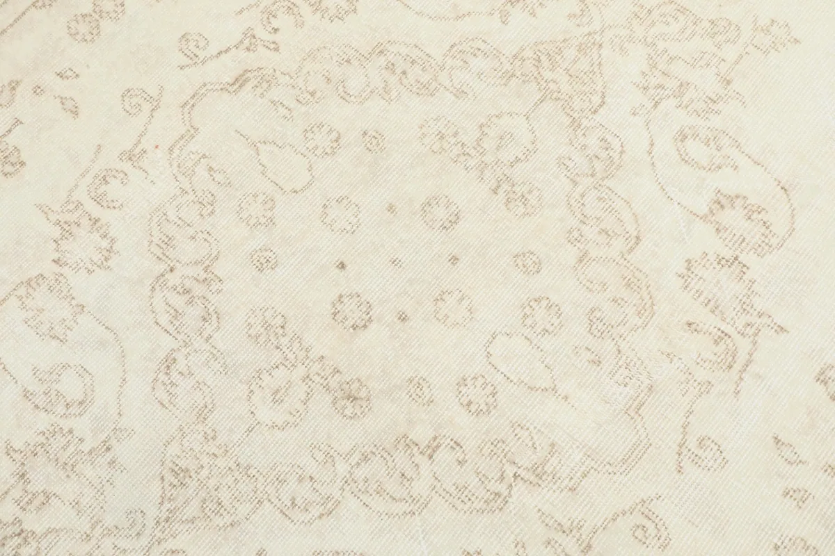 Detailed close-up of the central medallion motif, showing the faded beige floral elements.