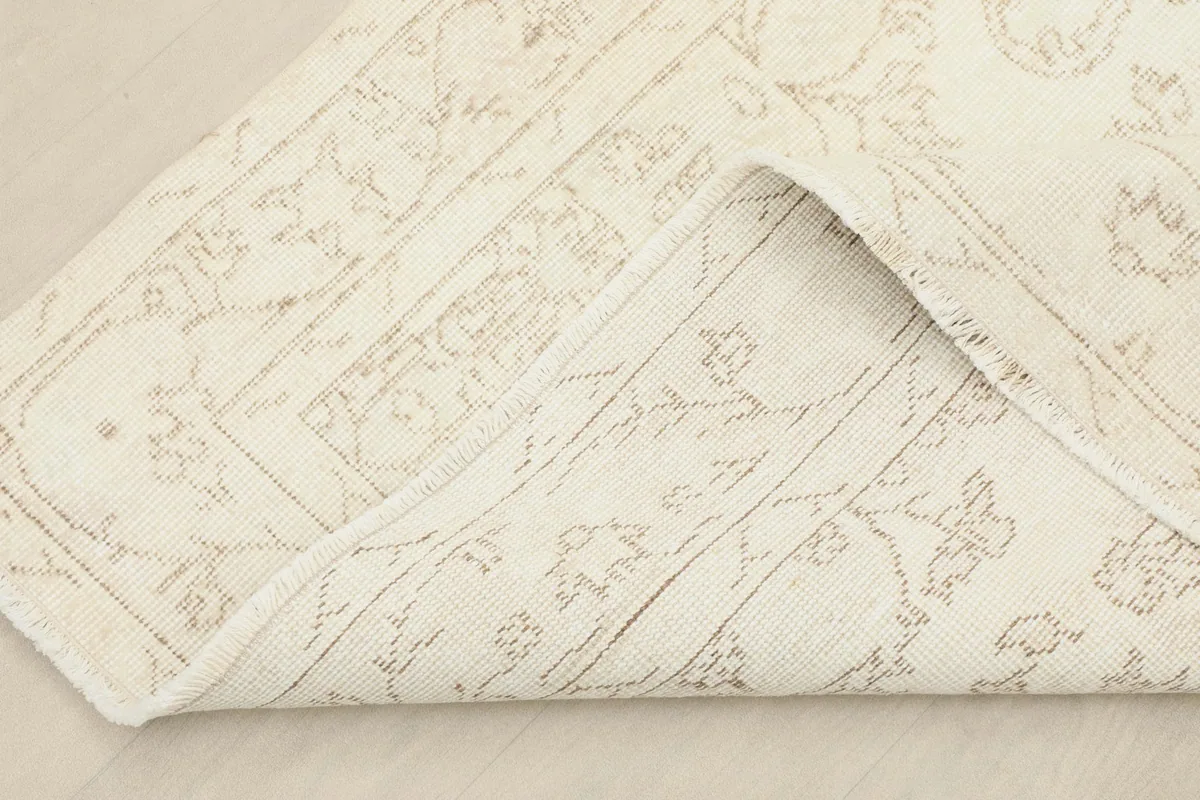 View of the rug folded back to show the cotton foundation and the reverse side of the hand-knotting.