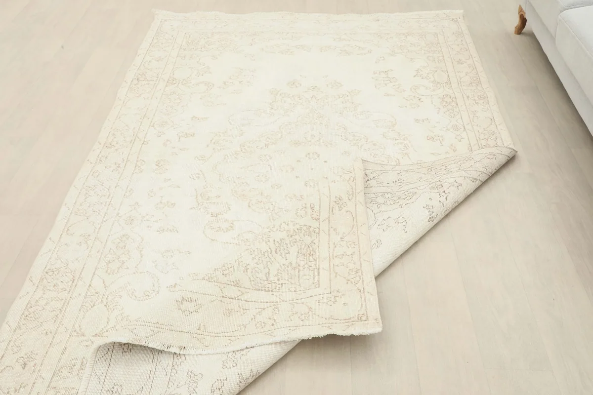 The rug partially folded, illustrating its flexibility and the natural drape of the vintage material.