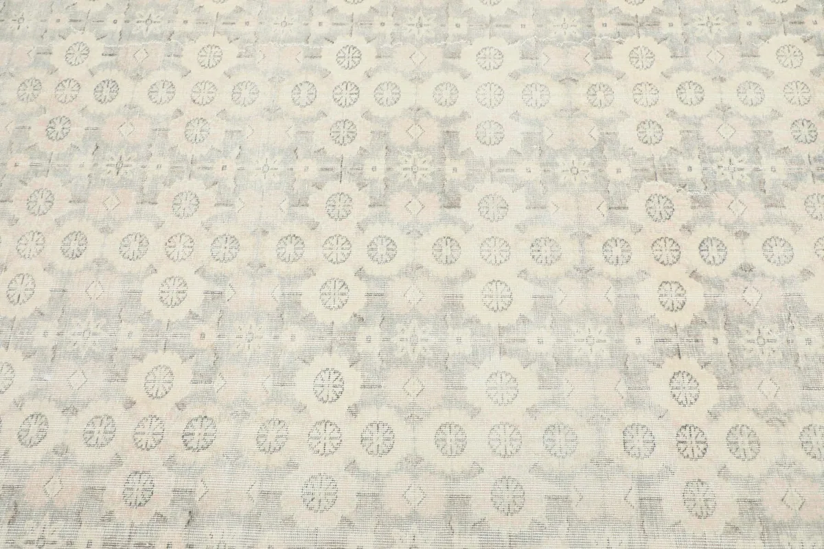 Close-up view of the central geometric medallion pattern with cream, gray, and hints of rose.