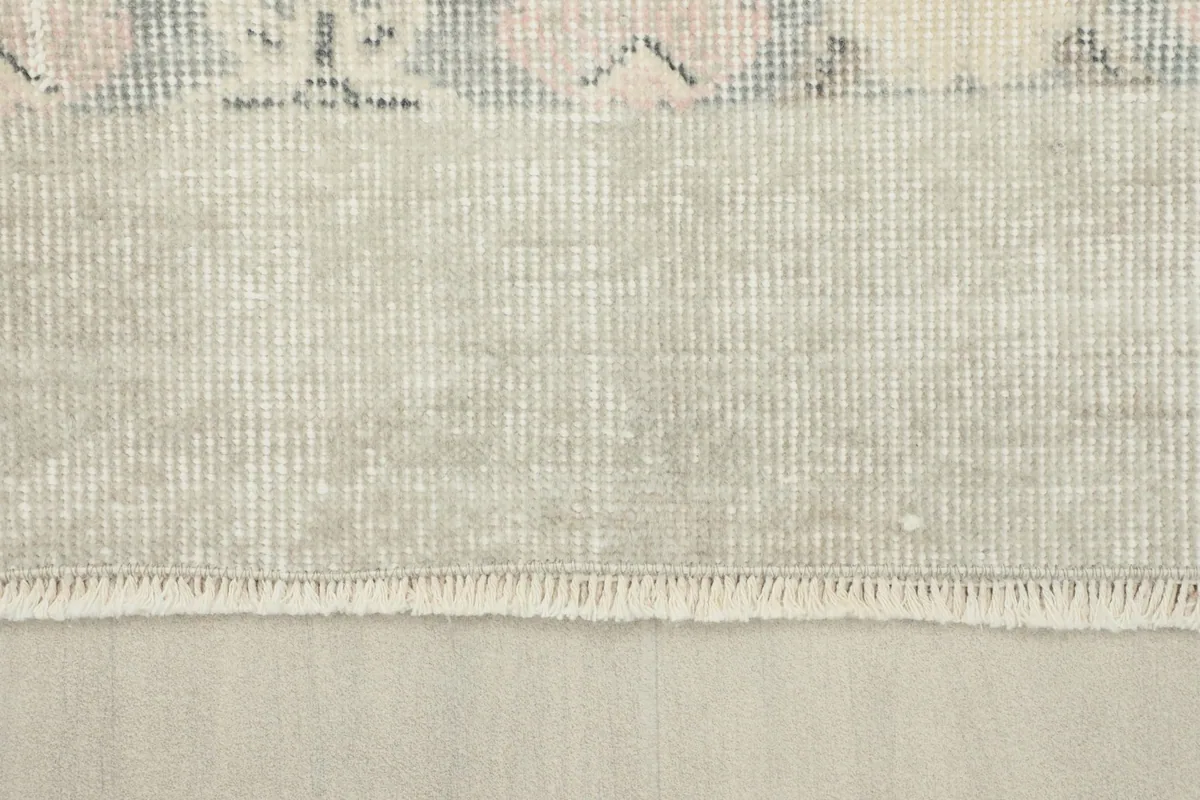 View of the rug's cotton foundation and the reverse side, showing the knotting structure and fringe.