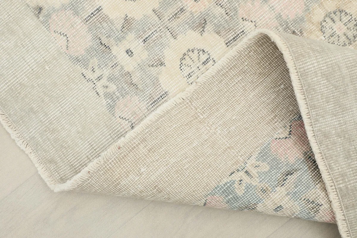 Corner of the rug folded back, revealing the wool pile and cotton foundation.