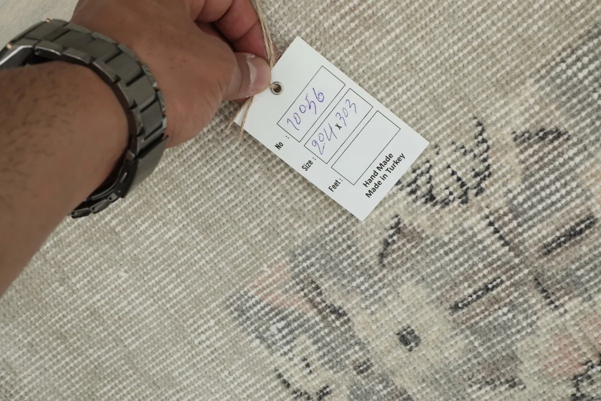 Hand holding a tag with the rug's identification number and size details.