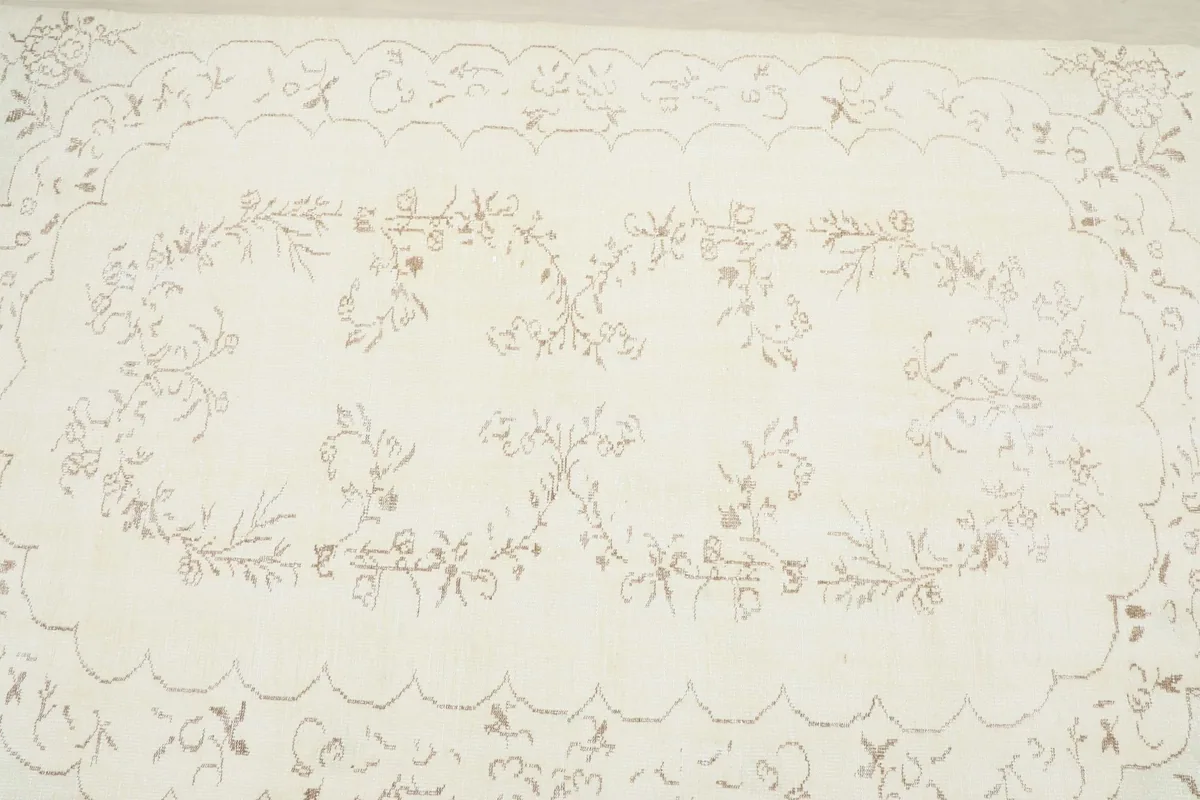 Close overhead view of the central floral pattern on the ivory field of the rug