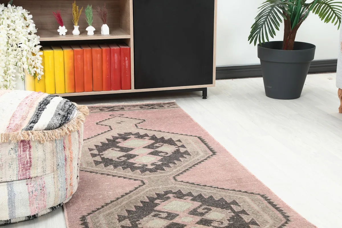 Close-up of the runner's end, showing rose field and charcoal geometric motifs near a pouf