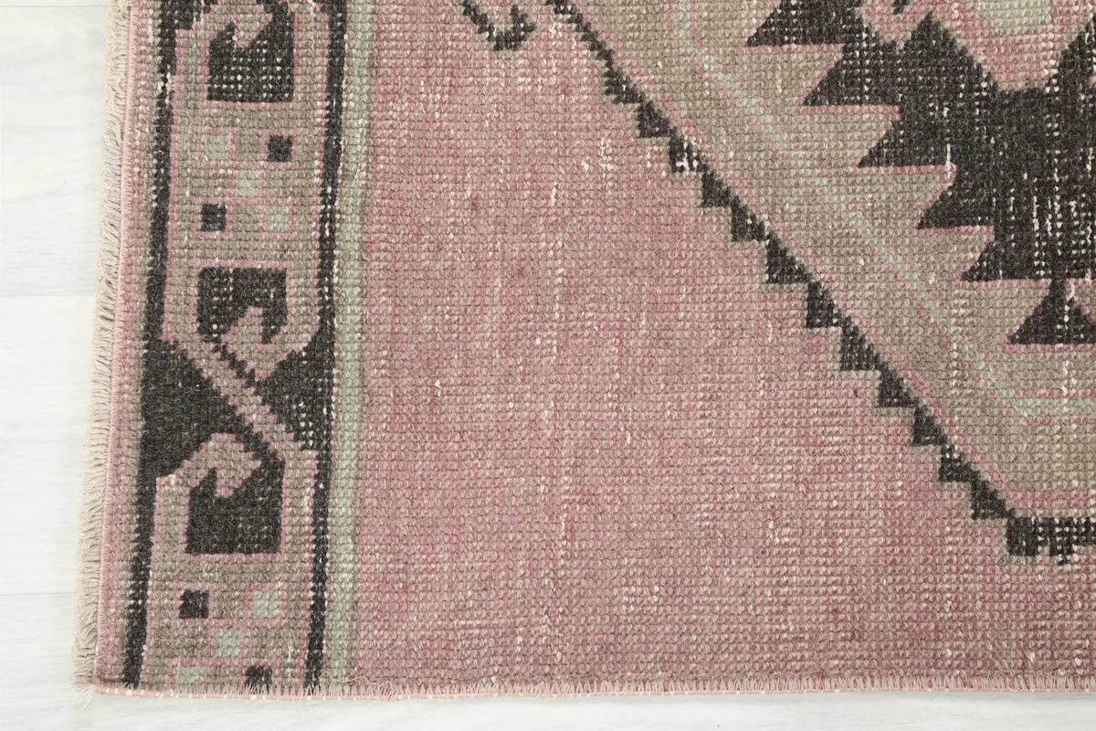 Corner detail showing the rose field, geometric border, and fringe of the vintage rug