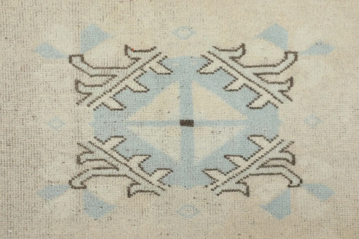 Detailed close-up of a central geometric motif in blue and ivory on the rug