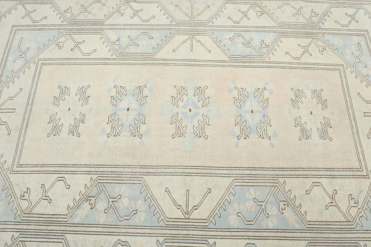 Close overhead view of the rug's central field with ivory and blue tribal motifs