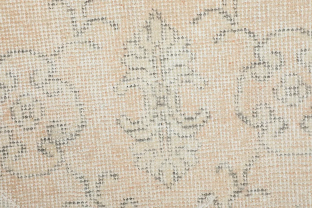 Close-up of the rug's low wool pile and the intricate, faded gray knotting of the floral pattern.