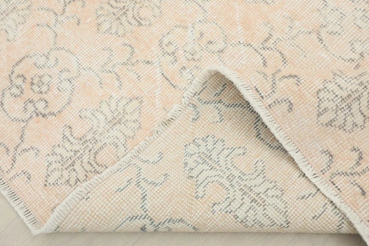 Corner of the rug folded back, revealing the cotton foundation and the reverse of the hand-knotting.