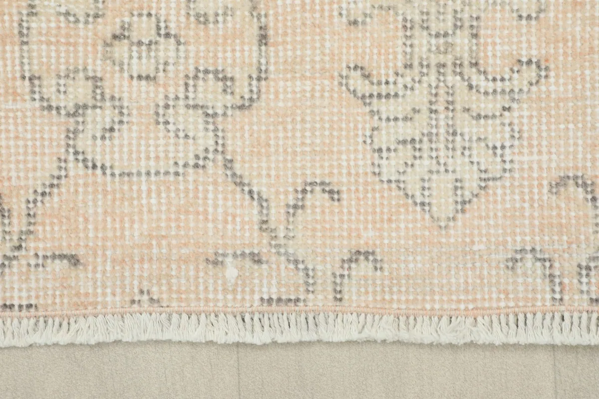 Detail showing the short, natural cotton fringe and the edge of the hand-knotted wool pile.