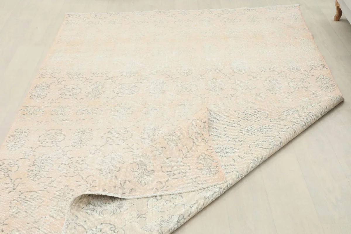 Rug partially rolled, showing the flexibility and the uniform thickness of the vintage piece.