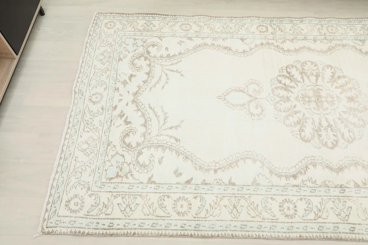 Angled view highlighting the faded tan and blue motifs within the rug's border