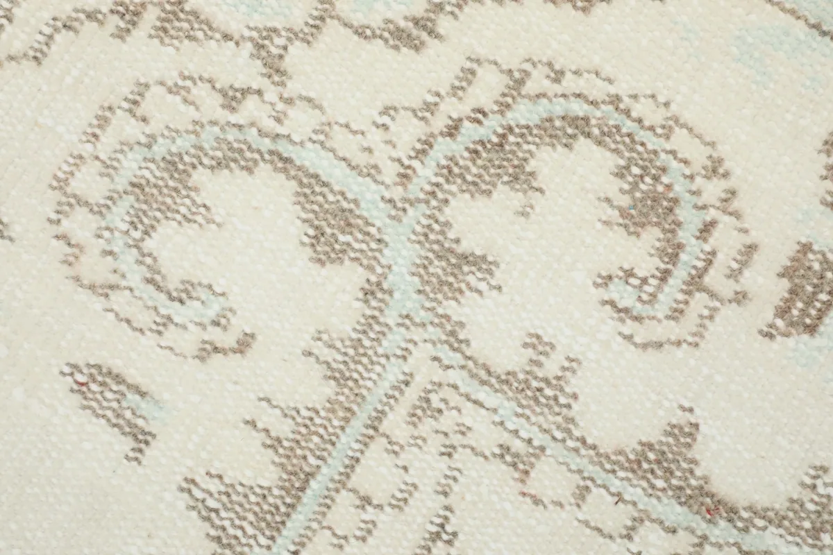 Macro detail of the hand-knotted wool pile showing the tan and blue threads