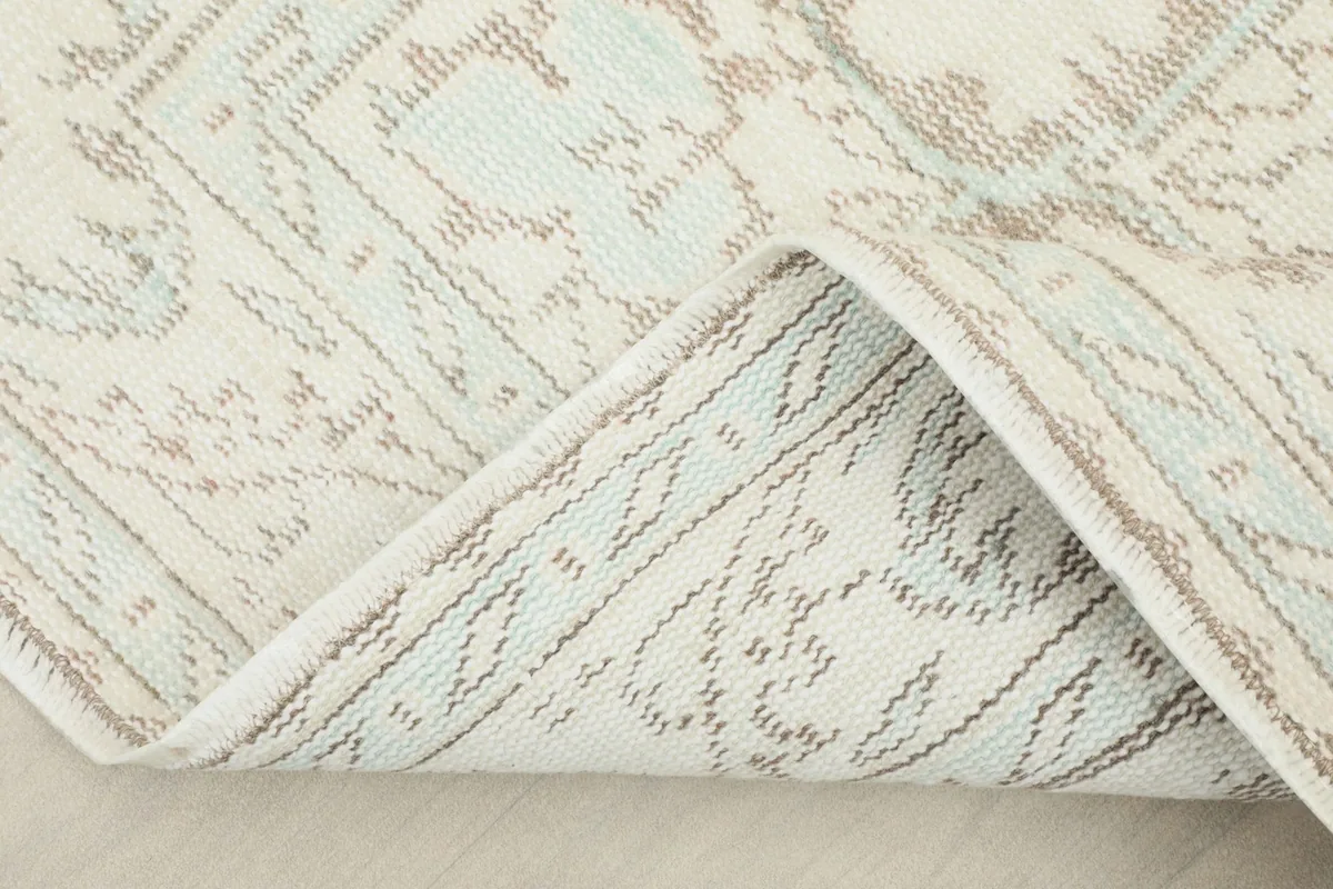 Corner of the rug folded back to reveal the cotton foundation and tight knots