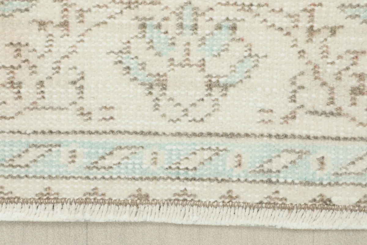 Close-up of the rug's short, natural fringe and the blue detailed border