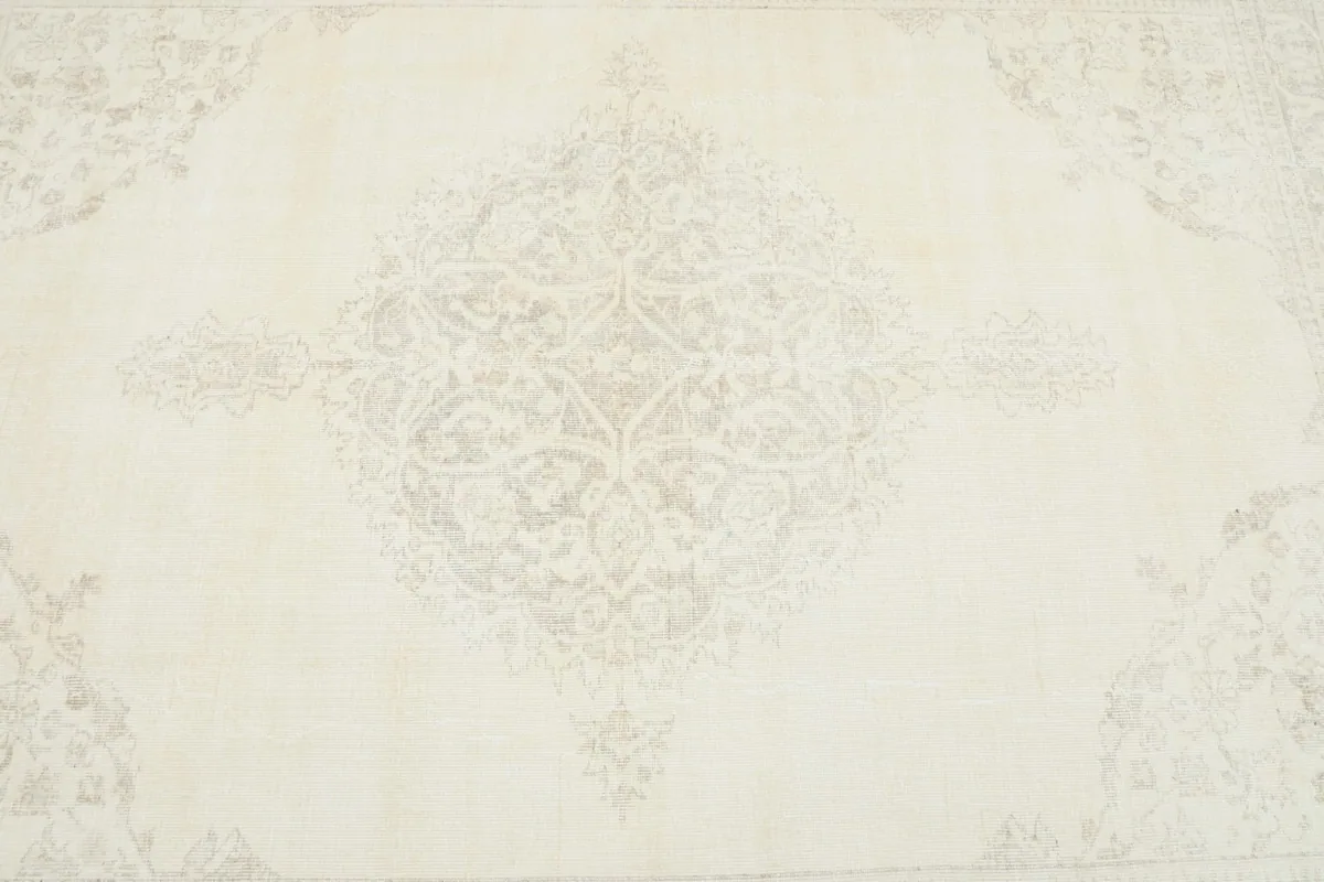 Detailed view of the central medallion design in faded gray on the ivory background