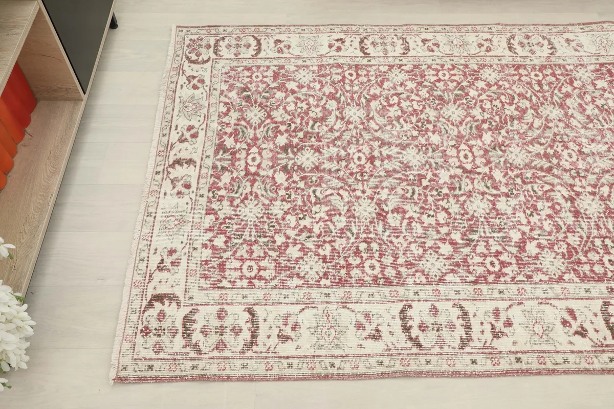 Overhead angle showing the floral and geometric motifs of the rose rug and its detailed ivory border