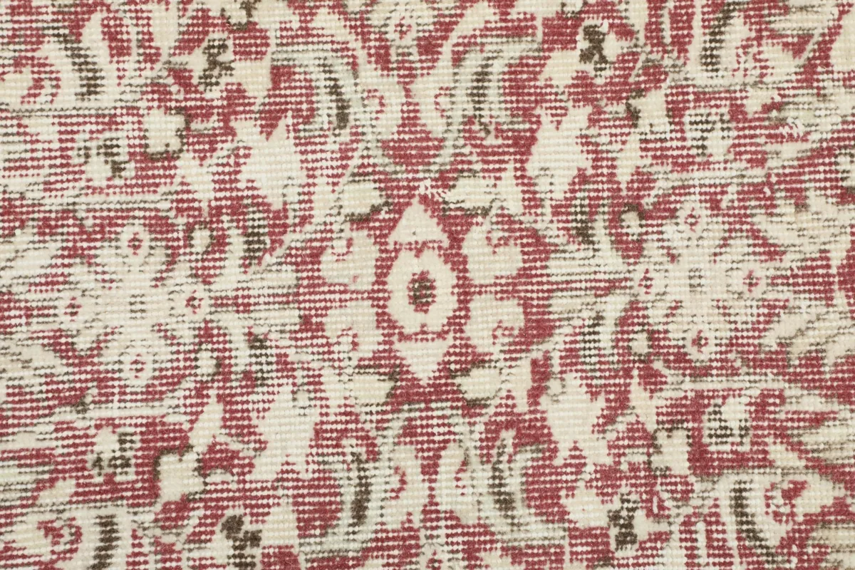 Extreme close-up of the vintage wool pile, showing faded rose and ivory colors and woven texture