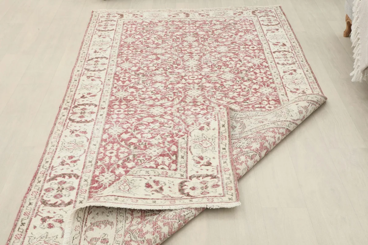 View of the rose and ivory rug with a corner folded back, showing the wool pile and cotton foundation