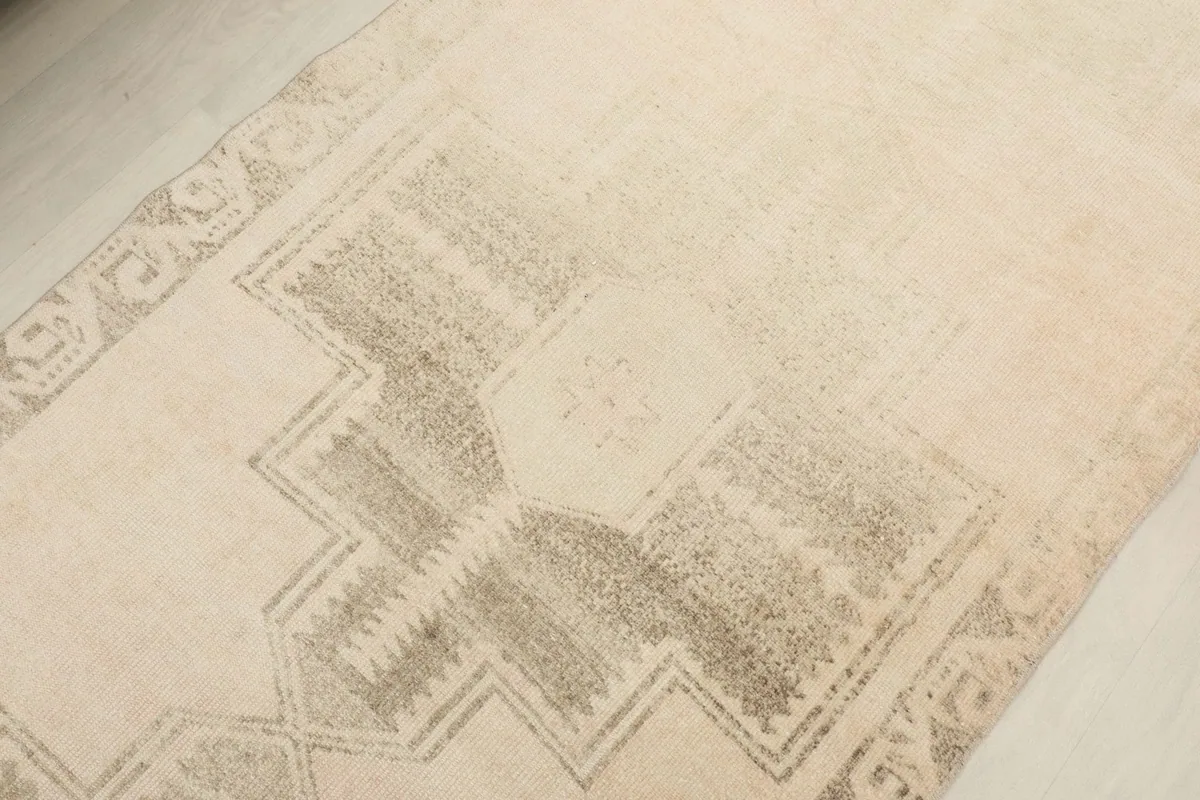 Angled close-up showing the faded gray geometric pattern and texture of the runner rug.