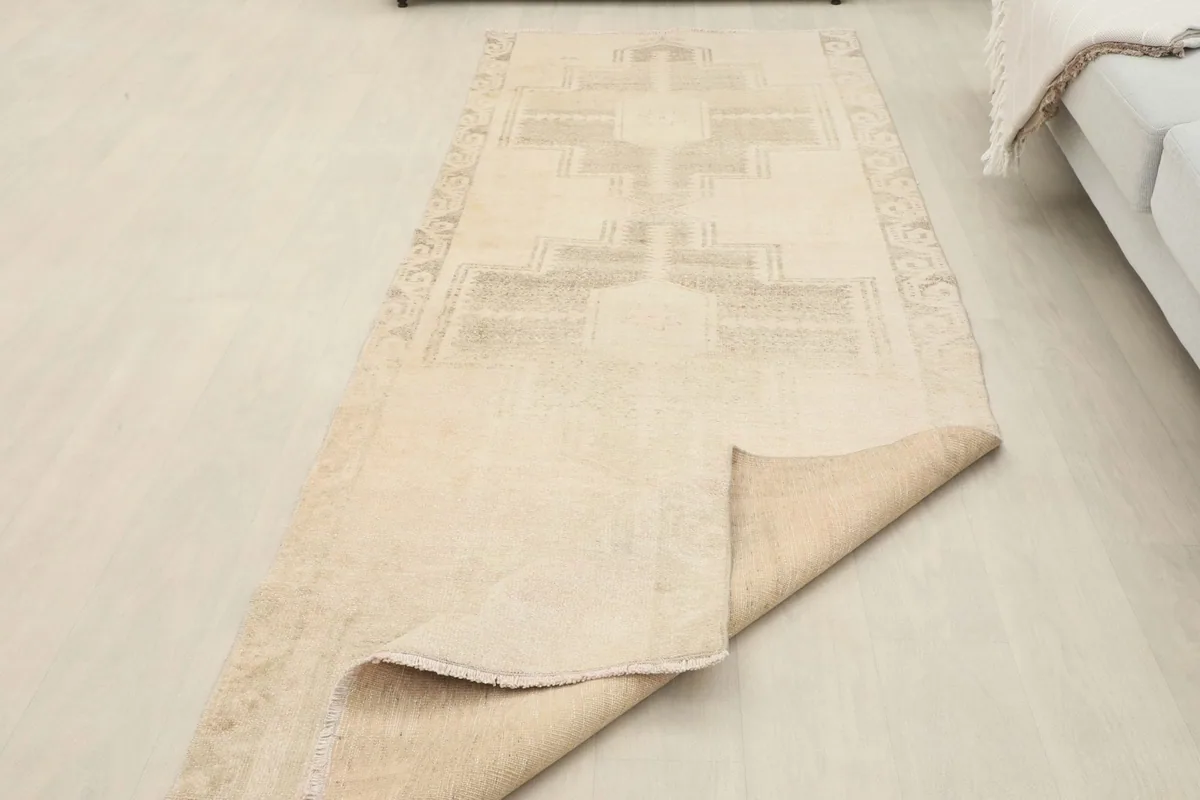 View of the runner rug partially folded, showing the reverse side and hand-knotted construction.