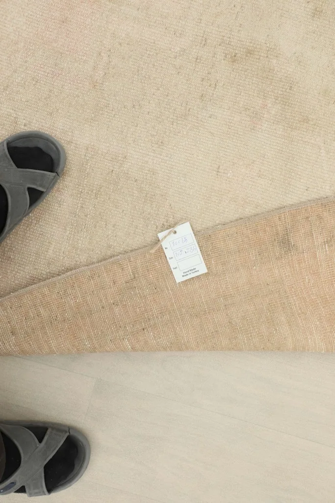 Top-down view of the rug with a size tag and feet for scale, showing texture.