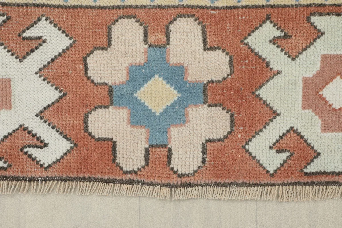 Detail of the rust border featuring blue, ivory, and pink geometric patterns