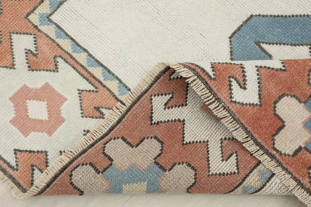 Folded corner of the rug revealing the wool pile and cotton foundation