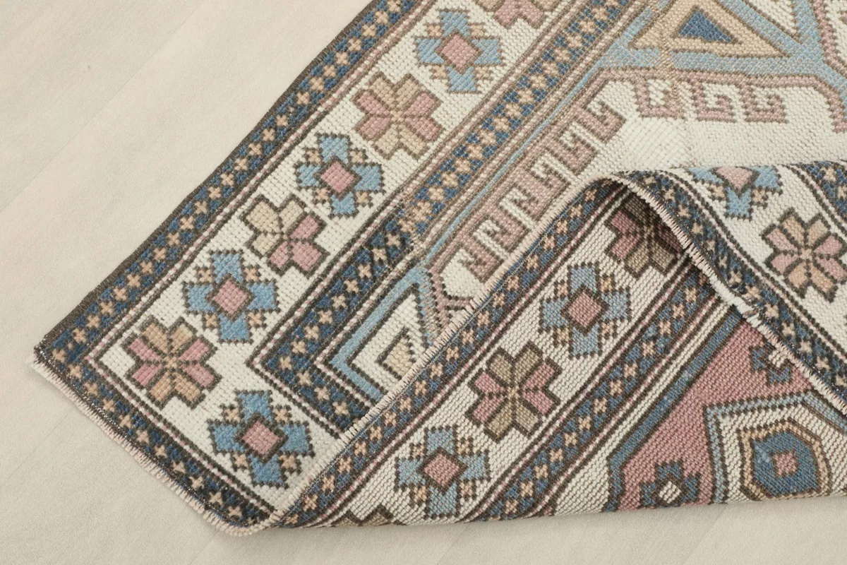 Corner of the rug folded back, showing the back of the hand-knotted wool pile and cotton foundation
