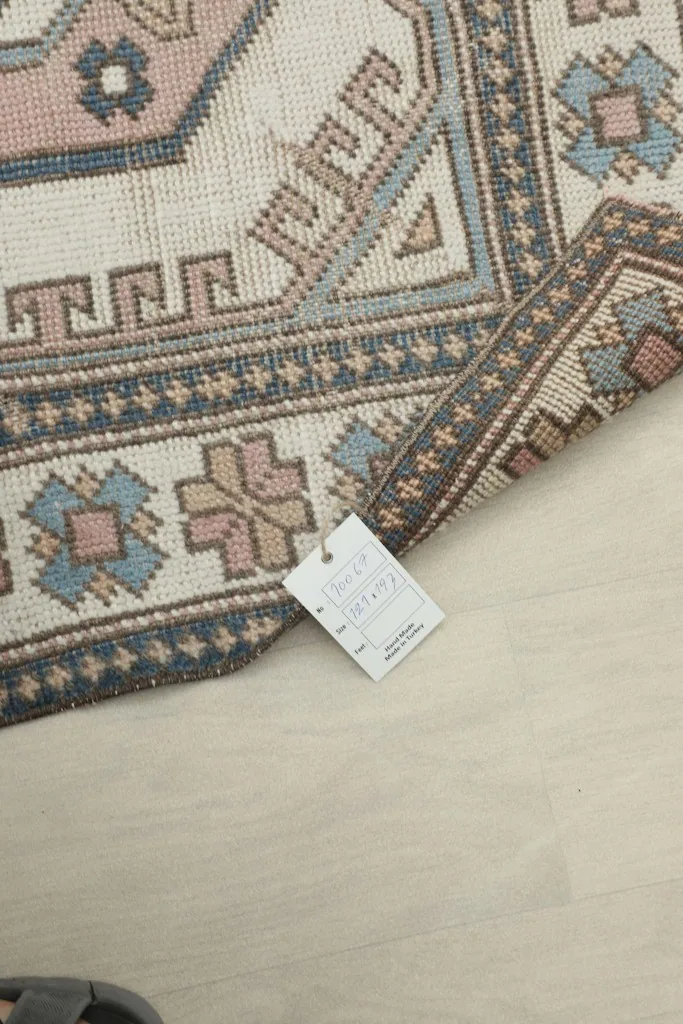 Rug corner with a product tag, indicating it is a hand-knotted vintage wool rug